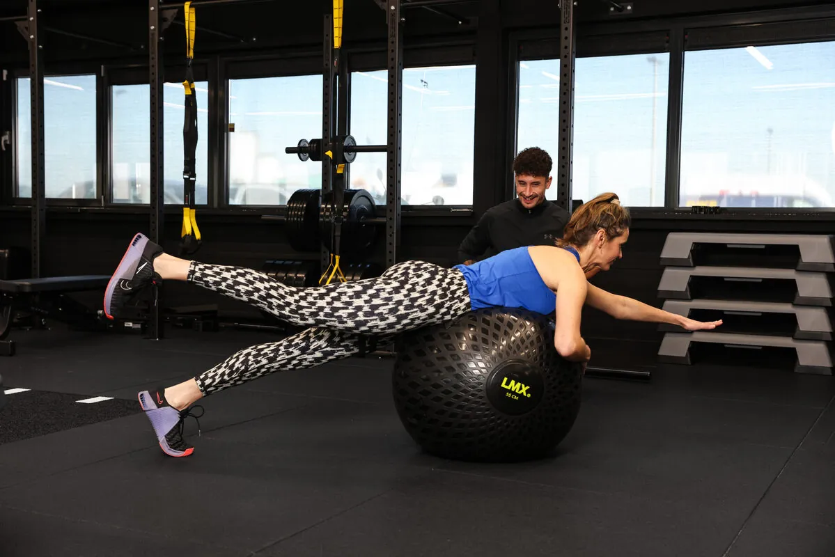 Klant houdt haar balans in een plank over de medicine ball