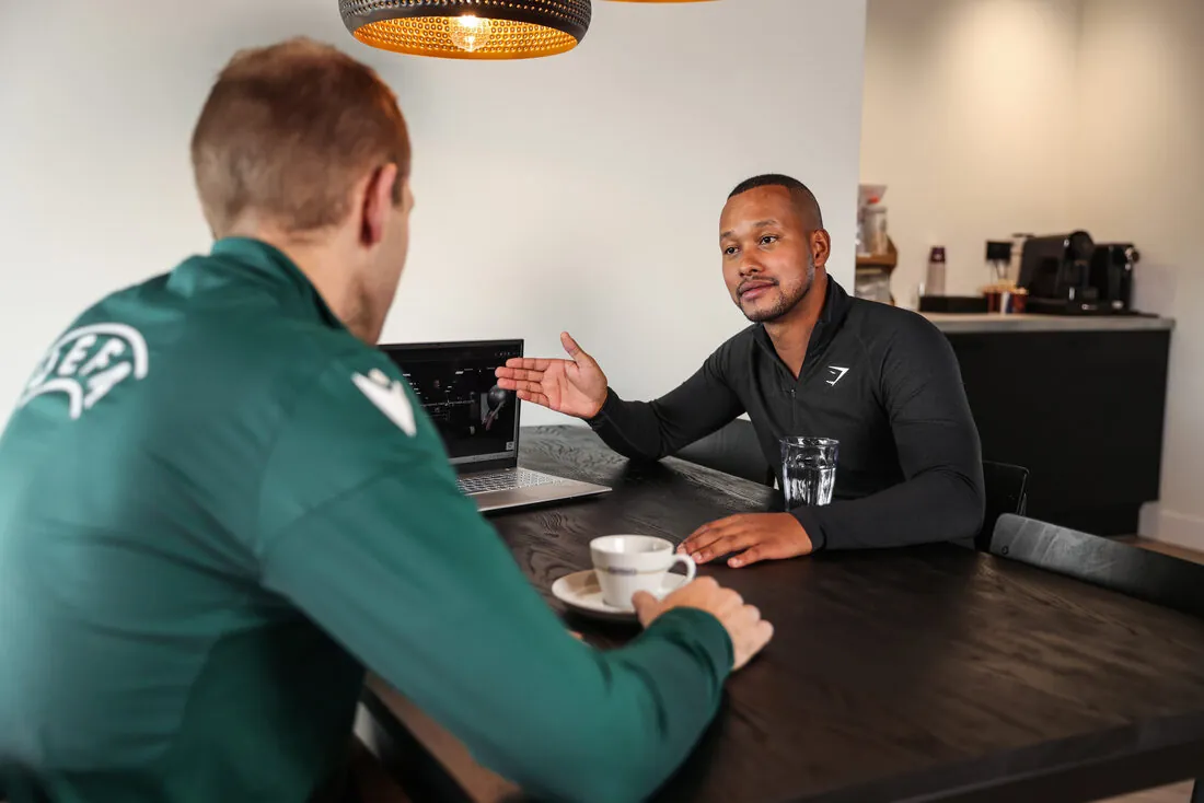 Kennismakingsgesprek aan tafel met koffie en laptop