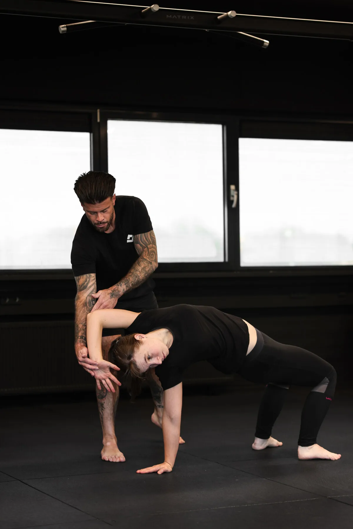 Trainer corrigeert hands-on de houding van een klant tijdens een oefening in de gym in Haarlem